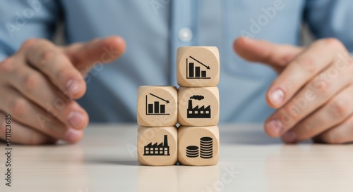Businessman's hands protecting wooden blocks with icons representing industrial decline, economic recession, and factory production crisis