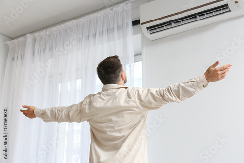 Young man near air conditio...
