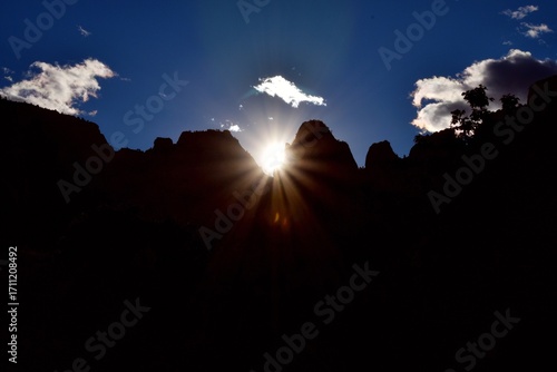 arafed view of the sun shining through the clouds in the mountains