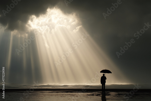 Person with umbrella standing on the beach during dramatic sunset