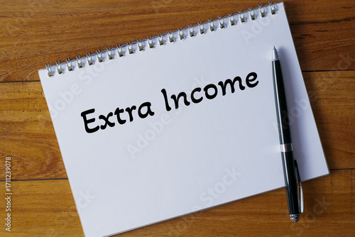 Extra Income written in a notebook on wooden desk