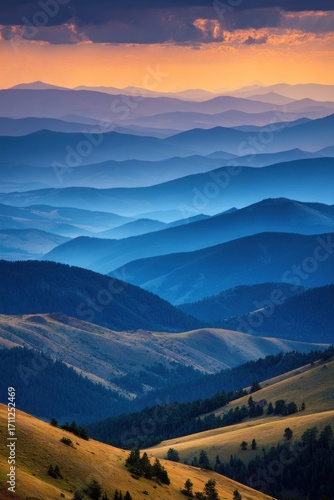 Layered hazy mountainscape glows with golden sunlight kissing the upper sky, fading into cool blues, with verdant hills below