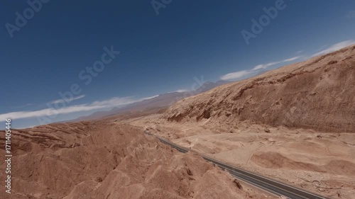 FPV drone shot flying along a winding road between sharp red rock formations in the Atacama Desert Chile during a breathtaking summer sunset with dramatic light and cinematic movements