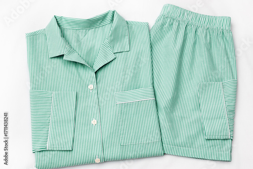 Green striped Pajama Set on white sheet background. Top view home sleepwear female from soft cotton trend mint green colored on bedclothes. Cozy pyjamas of shirt and shorts for comfort rest, flatly