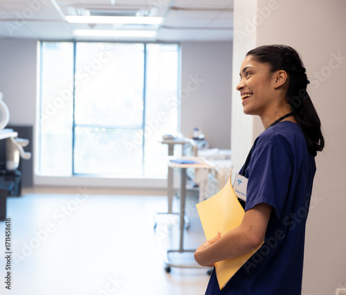 Smiling nurse holding patient files in hospital hallway, ready for rounds, copy space