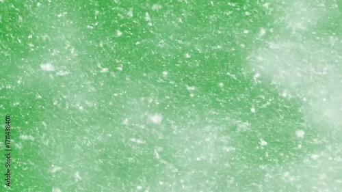 A heavy blizzard of snow fiercely blowing and swirling across a solid green screen for intense weather effects blowing, blizzard, snow