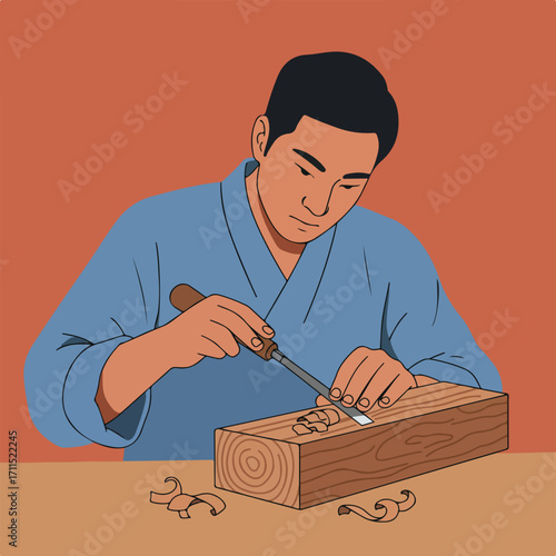 Man in a blue kimono carefully carves a wood block with a chisel. Wood shavings around block
