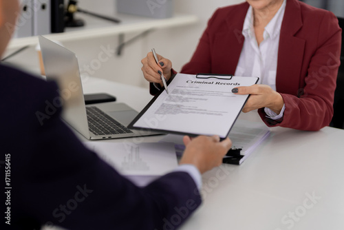 Legal professional client discuss criminal records document pointing pen during law office meeting consultation