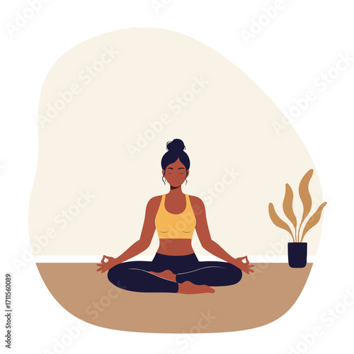 Woman sits cross-legged in yoga pose, eyes closed, with a plant, against a neutral background