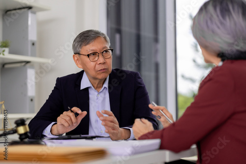 Experienced Asian legal advisor discusses case with client in professional office setting providing expert advice and solutions