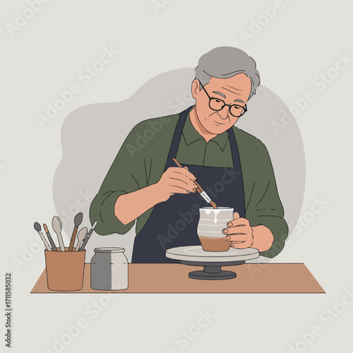 An elderly man wearing glasses, apron, and painting a ceramic pot on a pottery wheel