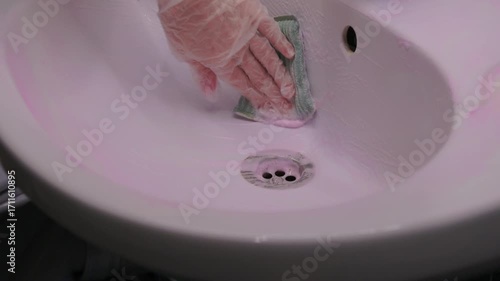 The process of cleaning a pink bathroom sink involves using a cloth to achieve a thorough clean