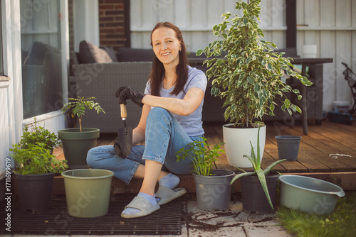 Happy woman gardening at home, repotting houseplant ion outdoor terrace at home
