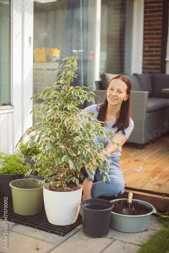 Happy woman gardening at home, repotting houseplant ion outdoor terrace at home