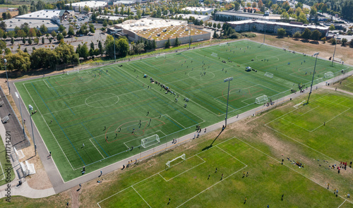 Aerial drone picture of a park in North Portland, OR, showing large soccer and football fields with kids playing matches on a weekend, community recreation and outdoor sports facilities captured