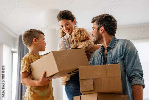 Fotografía Smiling man and woman enjoy unpacking with child moving to own home
