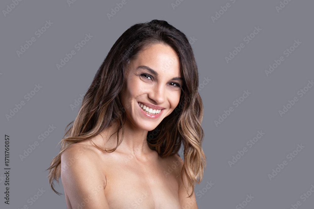Obraz premium Beautiful close-up portrait of a smiling woman on a gray