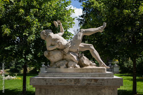 Classical marble statue surrounded by lush greenery in Uzutrakis manor park, Lithuania