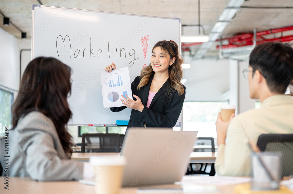 Naklejka premium Asian businesswoman holding document explaining marketing plan on whiteboard to coworkers in office.