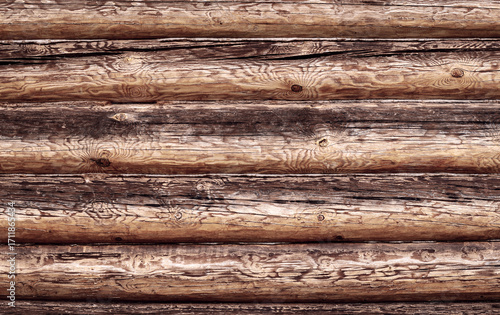 Abstract wooden background from logs. A wall made of old logs with natural patterns on the trunks. The logs are positioned horizontally to the background. Copy space.