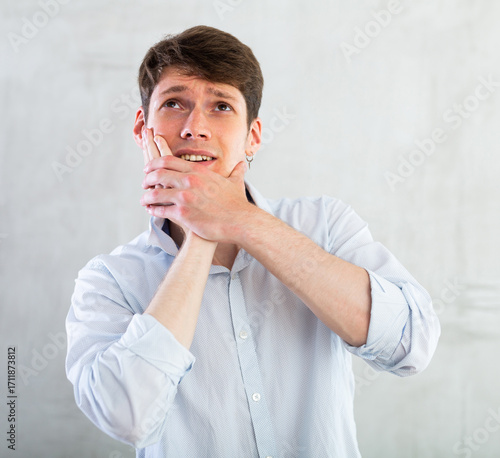 Unhappy man having a toothache in living room