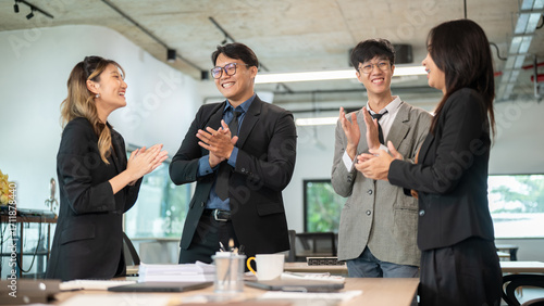Billede på lærred Smiling businessman and woman clapping hands with coworkers at wooden table endi