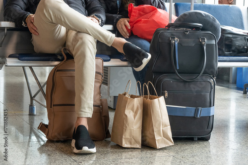 Anonymous passengers waiting with luggage and bags in an airport departure terminal.