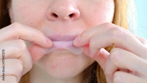 A girl puts a snoring patch on her mouth, close-up to sleep with her mouth closed and breathe through her nose. Healthy sound sleep with proper breathing. The toned oval of the face. Wellness