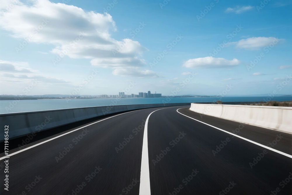 Fototapeta premium Smooth asphalt road stretching towards a scenic coastal view under a clear blue sky
