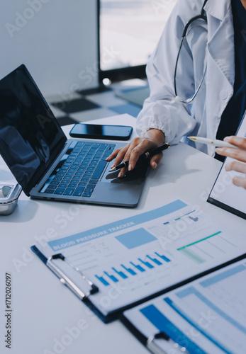 Medical team meeting analyzing blood test results in hospital laboratory. Doctors and scientists in lab coats are having a discussion about blood test result, holding test tubes and taking notes.