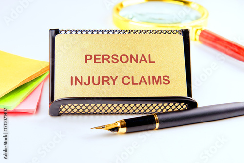 Legal services of lawyers for medical malpractice claims. PERSONAL INJURY CLAIMS words on a gold card on a stand with business accessories on a white background