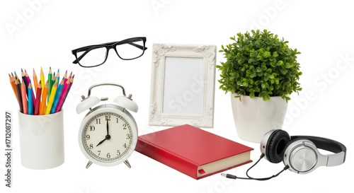 Isolated still life of desk objects featuring plant, headphones, book, frame, pencils, clock, and glasses