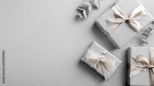 Elegant Gift Boxes with Neutral Ribbons and Eucalyptus Sprigs on a Soft Gray Background