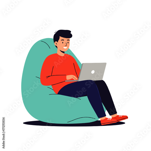 A young man sits comfortably in a beanbag chair, working on a laptop with a relaxed and happy expression.