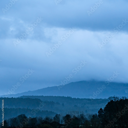 Sunrise on a cloudy day over mountains in the province of Salamanca, Spain, in shades of blue.