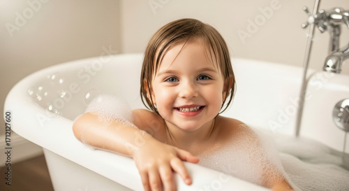 Joyful Little Girl with Wet Hair Smiling in a Bubble Filled White Bathtub During Bath Time at Home Happy Child Hygiene Portrait 