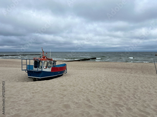 A fishing boat with equipment rests on the beach in Niechorze on the Baltic Sea in Poland