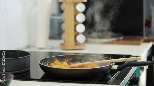 Woman frying veggies for stew at home