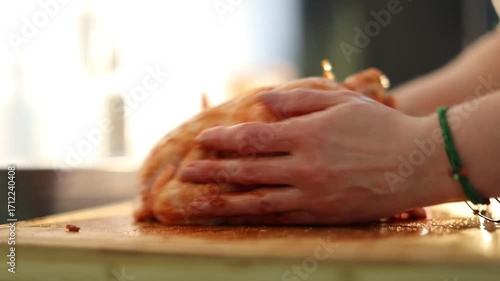 A woman is preparing a meal by carefully stuffing a whole chicken in her kitchen. The video shows the step-by-step process of home cooking, creating a cozy and appetizing atmosphere.
