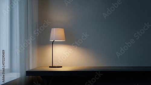 Modern floor lamp on a wooden table in a corner of a room. the lamp is turned on, casting a warm glow on the wall behind it.