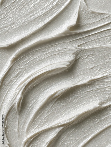 Close-up of creamy, off-white substance with swirling, textured strokes, creating a smooth yet dynamic visual