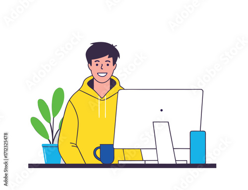 A smiling man in a yellow hoodie sits at a desk, happily working on a desktop computer
