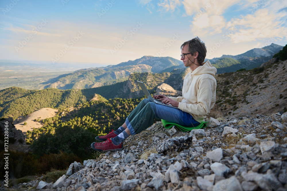 Naklejka premium Person Working Remotely on a Laptop in a Scenic Mountain Landscape