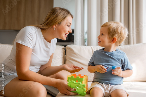 Mother and young child bonding while playing on a cozy living room sofa
