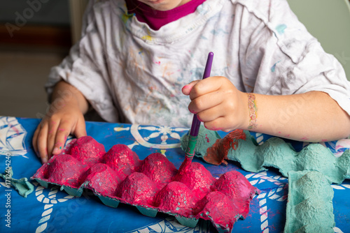 Child painting an egg box with a brush