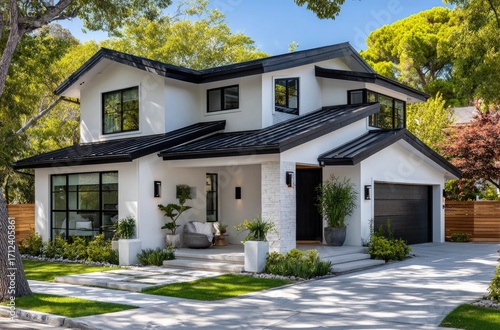a small, white two-story house with an l-shaped driveway and a wooden fence, featuring modern windows and black accents on the roof and walls.
