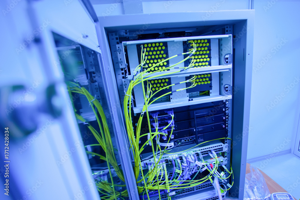 Fototapeta premium Blue Lit Network Equipment in Server Rack with Cables and Connections
