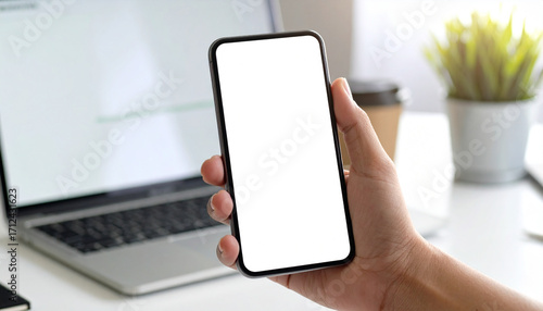 POV of a person using a smartphone and laptop at their workspace.Point of view