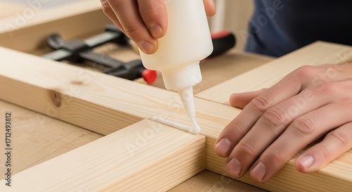 Carpenter applying wood glue to wooden planks.