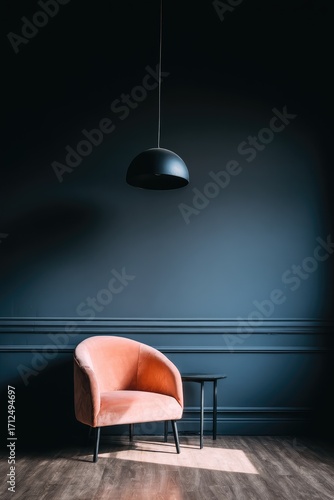 A stylish, modern interior featuring a blush pink velvet armchair, a dark gray wall with molding, and a simple black pendant lamp.